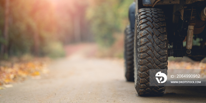 Part of an off-road vehicle on a rugged road in the forest . Travel concept with sunset and mountain