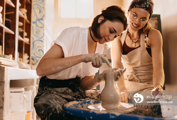 Two women at a pottery workshop making clay pots