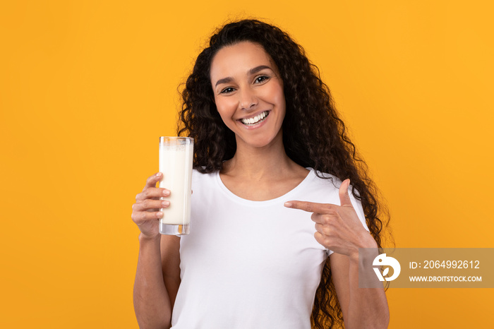 快乐的年轻女人在工作室指着牛奶杯