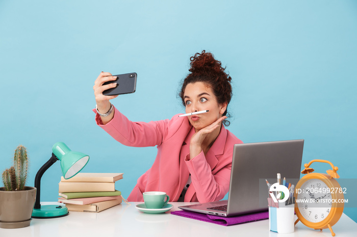 Image of amusing woman taking selfie photo on cellphone and grimacing