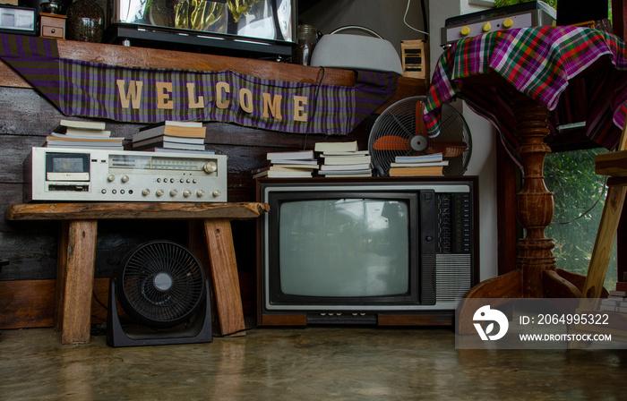 Antique and vintage style photo. retro televisions and radio pile on floor in old room.