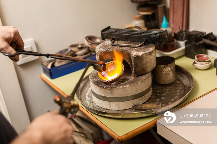 blowtorch melts silver in a jewelry workshop furnace