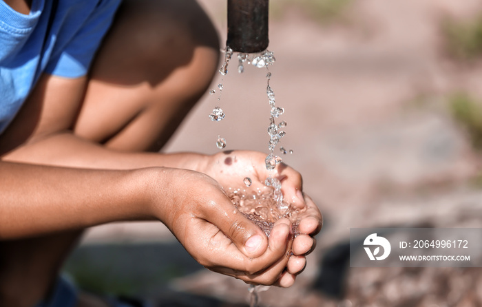 African American boy drinking water from tap, closeup