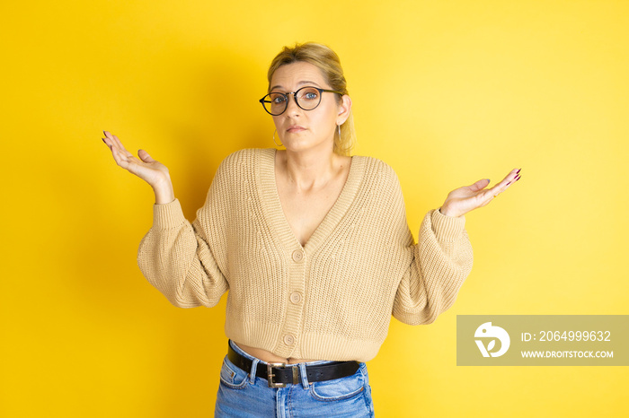 Young beautiful woman wearing casual sweater over isolated yellow background clueless and confused e