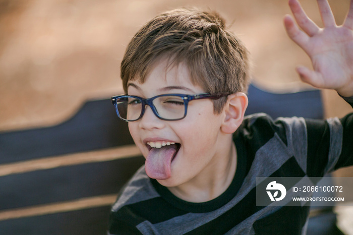 little boy in glasses making silly faces and sticking tongue out