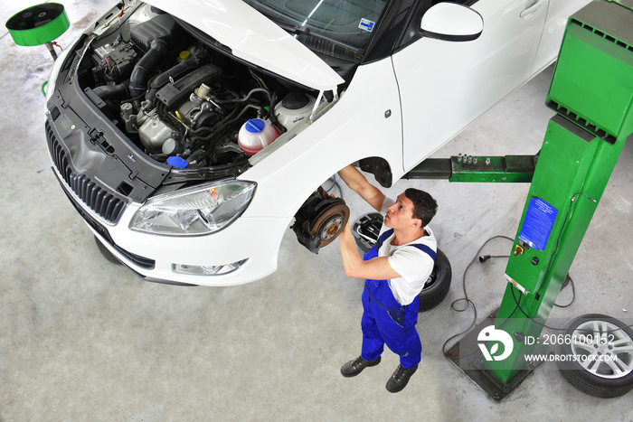 car mechanic repairs brakes of a vehicle on the lifting platform in a workshop