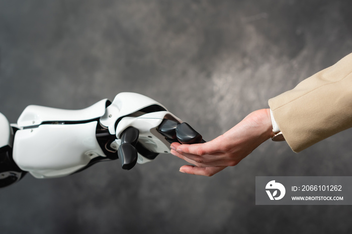 cropped view of businesswoman touching hand of humanoid robot