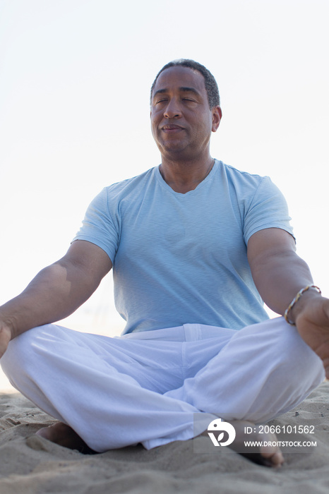 Serene senior man meditating on beach