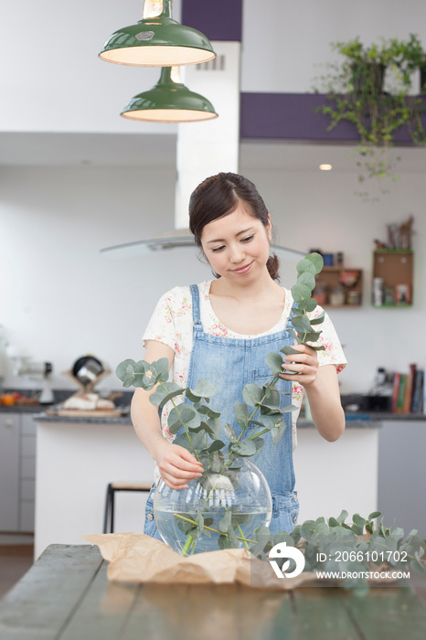 Young woman arranging foliage in vase