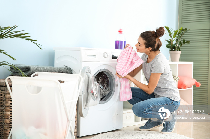 Beautiful young woman doing laundry at home