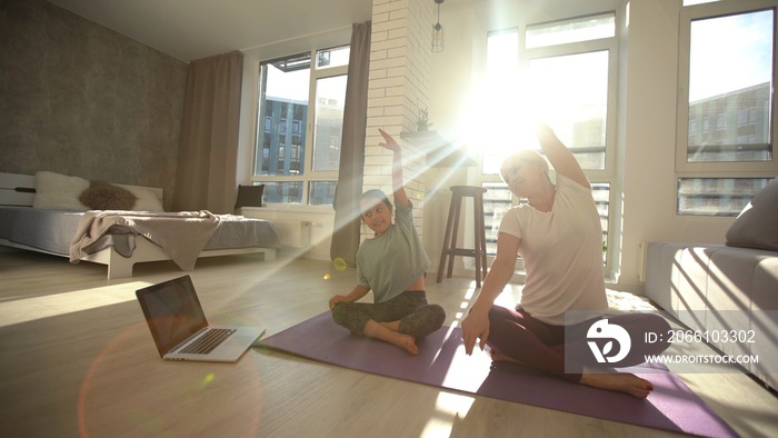 Young adult mother with her daughter watching online training together at home, looking a laptop