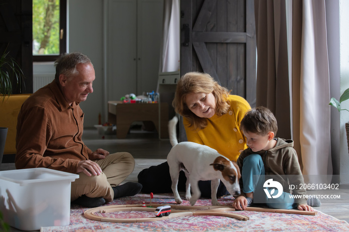 grandparents play the railway with their grandson at home.