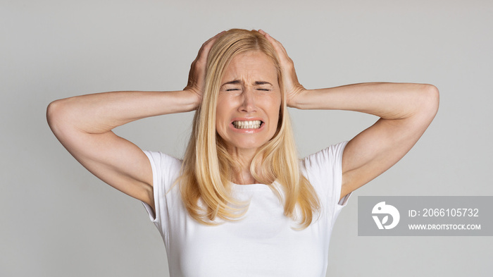 Stressed Mature Woman Covering Ears And Become Angry