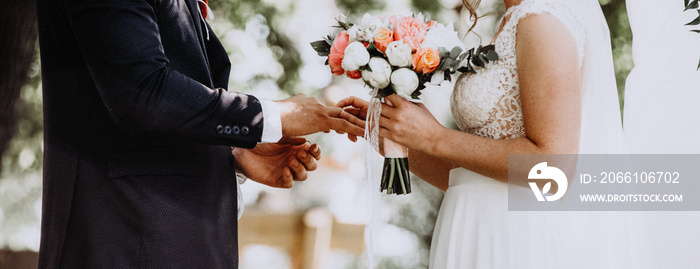 Wedding ceremony. Newlyweds exchanging rings, bride putting the ring on the grooms hand.