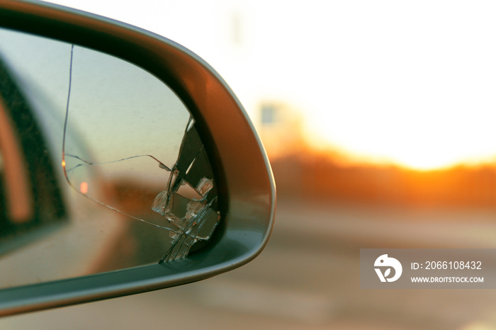 Side mirror of the car with a view back. Broken mirror close up.