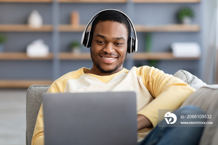 Closeup of happy black guy playing video games on laptop