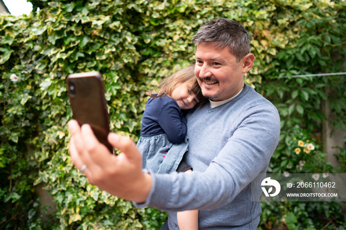 Smiling man taking�selfie�with daughter outdoors