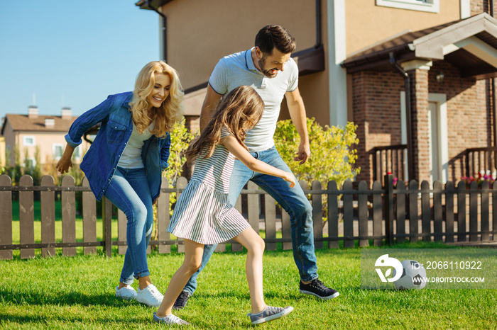 快乐的一家人在后院草坪上踢足球