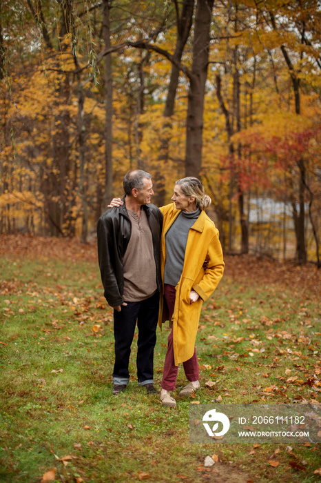 Full length of smiling couple standing in backyard during autumn