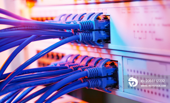 服务器机架，带有蓝色和红色互联网跳线电缆，连接到数据服务中的黑色接线板
