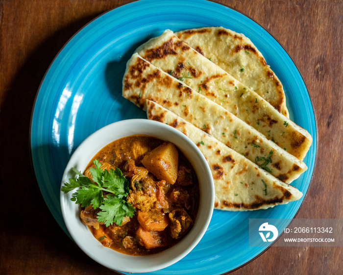 flat lay of garlic butter naan served with chicken curry stew