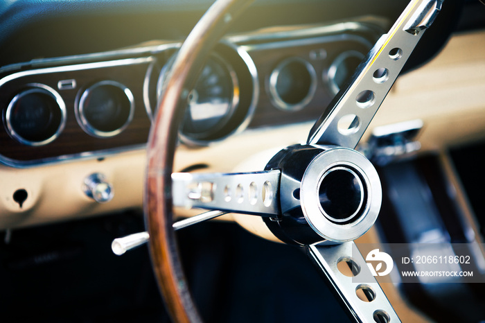 Inside view of classic american muscle car, with focus on steering wheel.