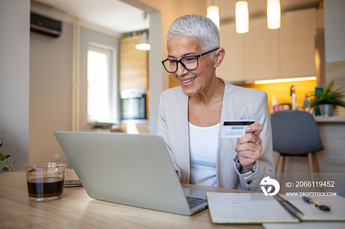 在家使用信用卡进行在线支付的成熟女性。成功的老妇人在网上购物