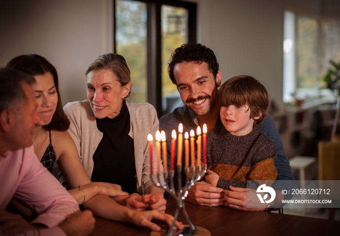 Cute boy with happy family at table during Hanukkah festival