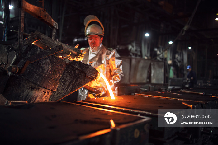 Foundry workman pouring molten iron into molds for steel production. Heavy industry and metallurgy p