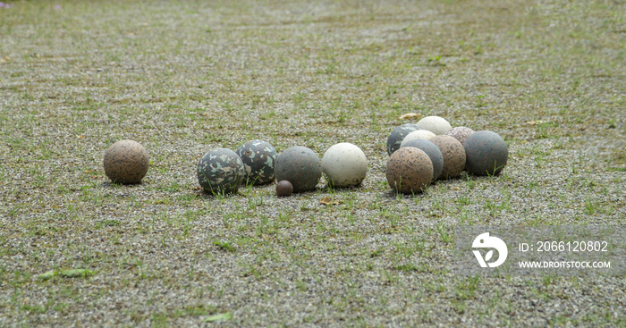 Boules en pierre et un petit cochonnet en bois sur le terrain de pétanque dans un jardin