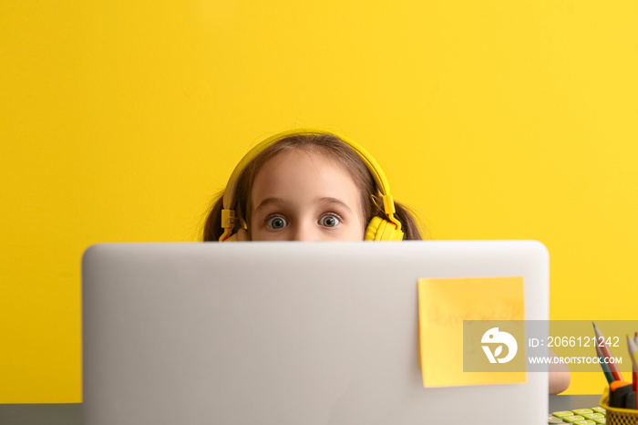 Little girl with laptop on color background