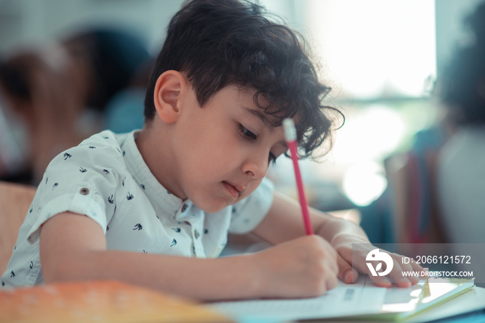 School boy writing his test during the lesson.