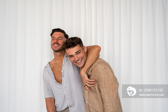 Beautiful Gay couple arm around shoulder and happy with white curtain background