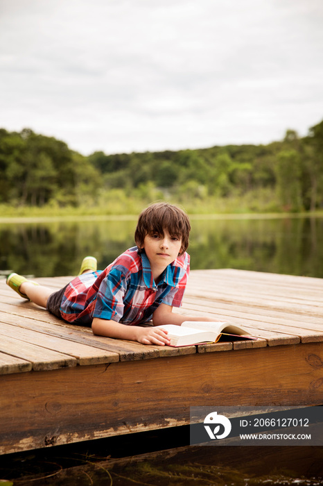 Portrait of boy lying on wooden jetty