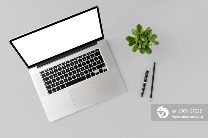 Overhead shot of laptop with empty screen and accessories on white desktop. Business background. Fla