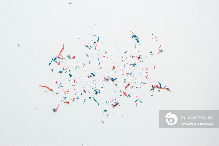 Closeup of pink and blue eraser dust sitting on top of a with sheet of paper – Small residual trash 