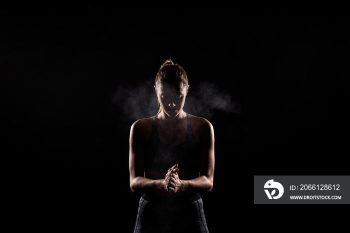 silhouette of sportswoman applying talcum powder to hands on black