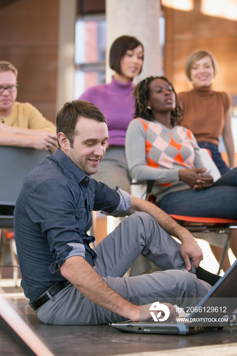 Man sitting on floor with laptop during presentation.