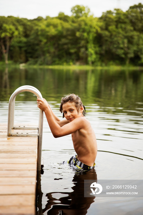 Portrait of boy holding handrail in lake