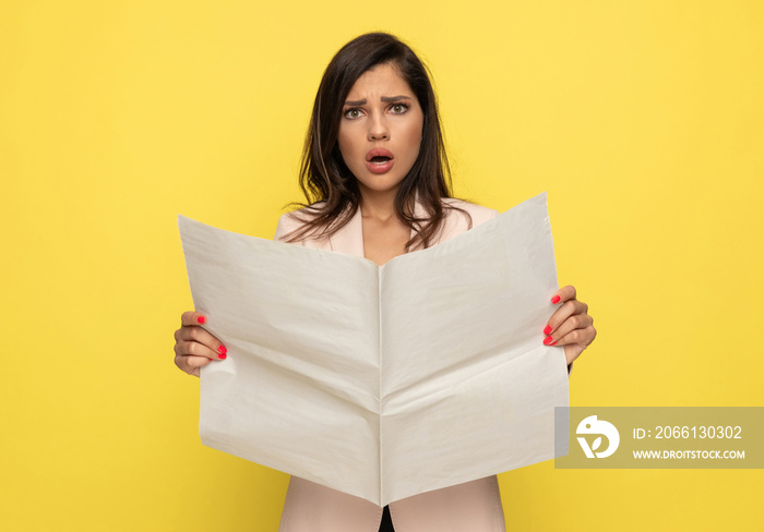 upset young woman in pink suit reading newspaper