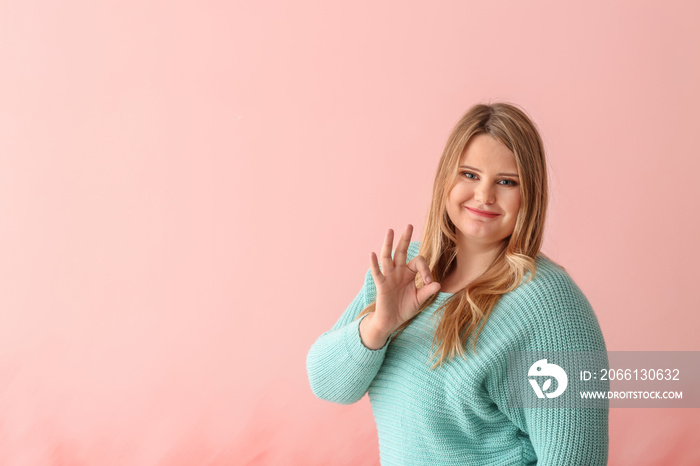 Beautiful plus size girl showing OK gesture on color background. Concept of body positivity