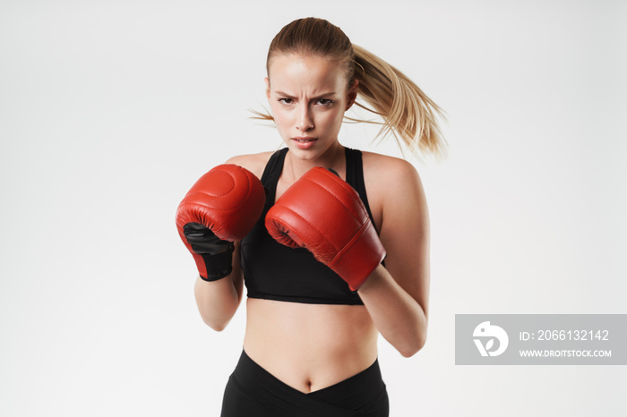 Image of serious blonde woman wearing tracksuit boxing with gloves while training