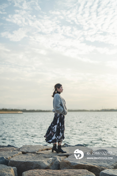 冬の夕暮れの海にいる女性