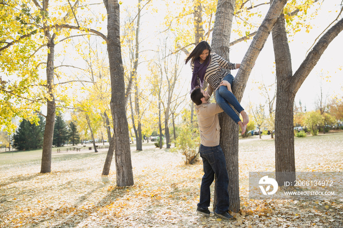 Young man helping woman to get down from tree