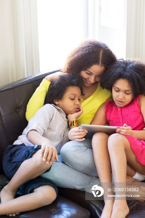 Mother using tablet pc with children (6-7, 8-9)