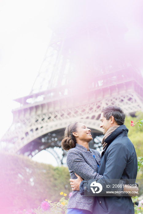 Affectionate couple hugging below Eiffel Tower, Paris, France