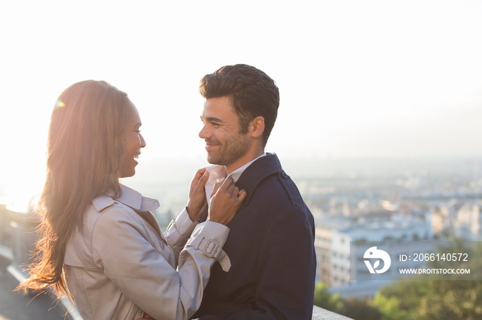 Affectionate couple hugging on sunny balcony, Paris, France