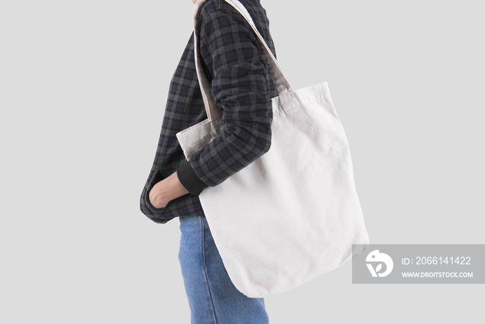 女孩拿着一个帆布包，用于隔离在灰色背景上的模型空白模板。