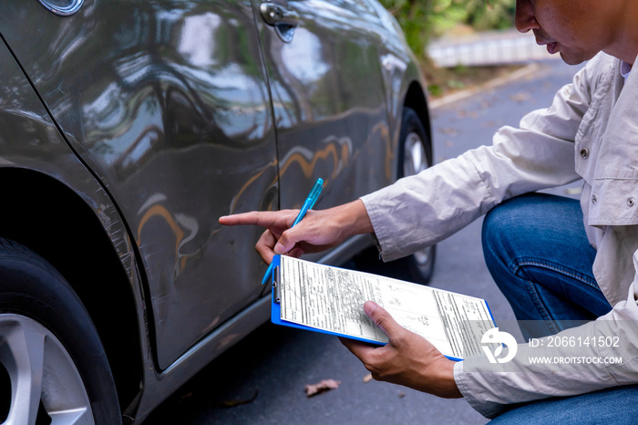 保险代理人在评估和公关事故索赔后检查汽车时在剪贴板上写字