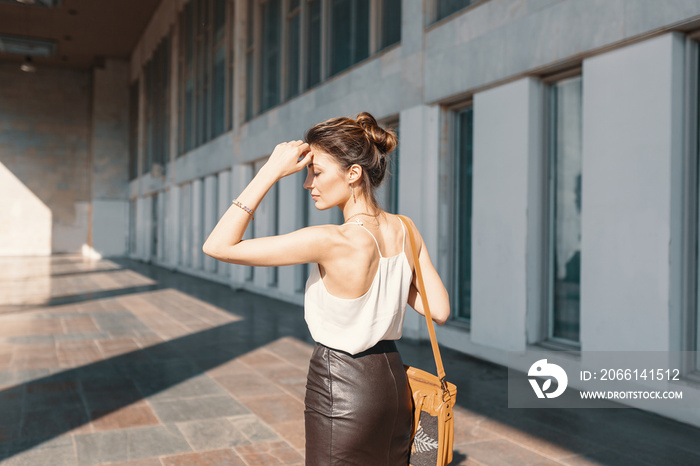 Refined young woman in leather skirt and silk blouse thinking how to solve a situation.